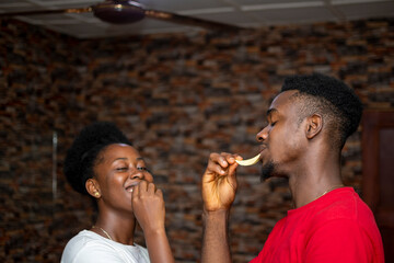 two young african people smiling while eating chips