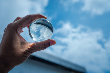 The hand was holding a glass ball and shone at the blue sky.