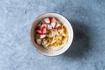 Oatmeal Porridge Bowl with Apple slices and Honey.