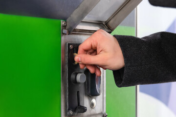 Close up of hand inserting coin into slot machine at car wash. Self service.