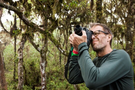 Ecuador, Galapagos Islands, Man taking pictures with digital camera on hike in jungle