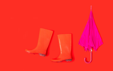 Rubber shoes and umbrella isolated on red background. Rain season and weather forecast. Nobody