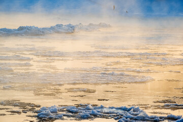 Melting cracked ice flowing down the river on a foggy morning. Misty water surface at the end of winter. Ice drift.