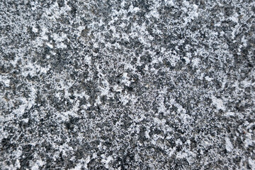 Salt spread on icy pavement in the city. Bricks covered with salt stains. Slippery sidewalk in winter.