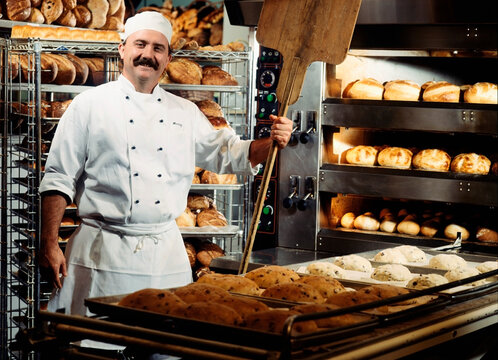Portrait of a baker standing in a kitchen with breads