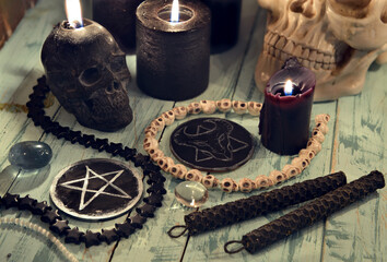 Pentagram and devil symbols with black burning candles on witch wooden table.