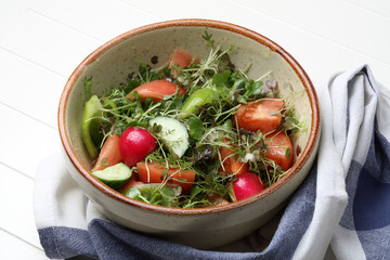 Simple homemade salad with tomatoes, cucumbers, bell peppers, radishes, microgreens and olive oil