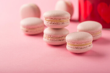 Rose macaroons present in festive gift box on pink background, copy space.