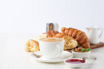 Fresh delicious breakfast with Coffee, crispy croissants, jam on white wooden background.