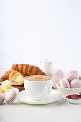 Fresh delicious breakfast with Coffee, crispy croissants, macaroons, jam on white wooden table.