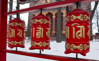 Fototapeta na wymiar Red prayer drums near Buddhist temple in St. Petersburg, Russia. This beautiful religious building (The Datsan Gunzechoinei) is located on Primorsky Avenue, not far from Yelagin Island.