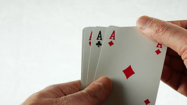 Hands unveiling an aces poker (four of a kind) on a white background