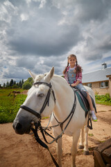 Fototapeta premium A teenage girl and a horse in nature among green trees