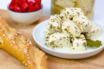 Artisan soft sheep cheese made on a Slovak farm marinated in a salty brine with herbs a bay leaf. Presented on a white plate with a bread roll. 