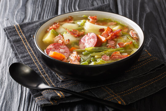 Luxembourgish Bean Soup Bouneschlupp with bacon, potato, sausages and onions close-up on a plate. Horizontal