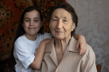 Little baby girl and very old woman. Little child hugging grandmother. Granddaughter