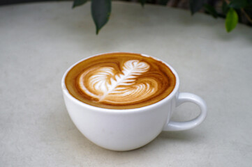 Hot coffee, cappuccino in a white mug placed on the table.