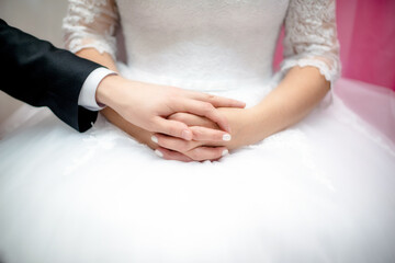 Fototapeta na wymiar The groom holds the hand of the bride in a white dress 