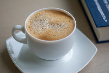 Cup of Morning cappuccino coffee with milk and blue book photography