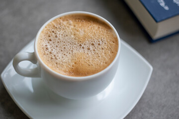 Cup of Morning cappuccino coffee with milk and blue book photography