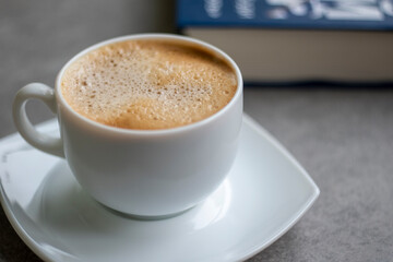 Cup of Morning cappuccino coffee with milk and blue book photography