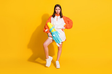 Fototapeta na wymiar Photo portrait full body view of amazed pouting woman holding water gun in one hand isolated on vivid yellow colored background