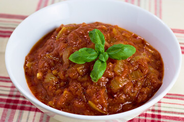 Closeup of a bowl with home cooked marinara sauce garnished with basil