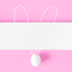 Creative Easter layout with egg and bunny ears on light pink background. Flat lay, copy space. Happy Easter holiday