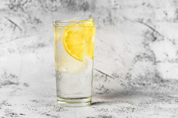 A glass of water with ice and lemon on a gray background, the concept of a proper healthy lifestyle