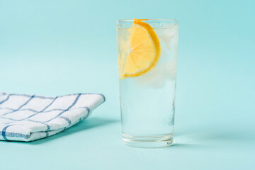 A glass of water with ice and lemon on a light blue background, the concept of a healthy lifestyle