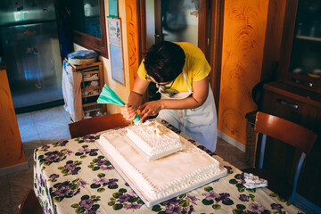 Woman making delicious pie on kitchen table, pastry chef applies cream to cake