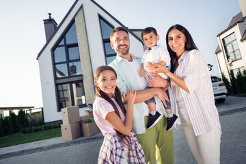 Photo portrait of full family wife embracing husband keeping son smiling with small daughter outside new house in summer