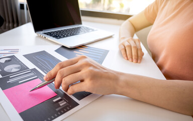 graph paper, Asia woman hand holding pen, analysis the graph with calculator and laptop at the home office for setting challenging business goals And planning to achieve the new target