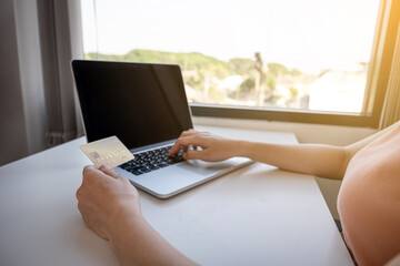 Young Asian consumer woman hand holding a credit card, Ready to spending pay online shopping according to discount products via smartphone and laptop from home