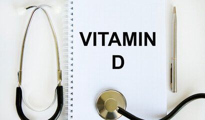 In the notebook is the text of VITAMIN D, next to a stethoscope and a pen.