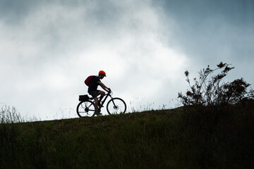 Naklejka premium Silhouette image of a cyclist riding the Otago Central Rail Trail against the cloudy sky, South Island, New Zealand