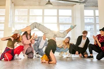 Aluminium Prints Dance School female hip hop dancer in motion, standing upside down, showing break dance for people surrounding dancer, performance in studio