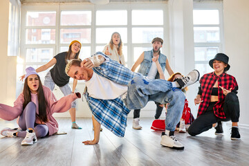 man making hip-hop movements during the rehearsal in studio, caucasian trendy youth perform modern dance