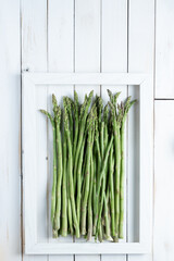 Asparagus in a frame on white old wooden board