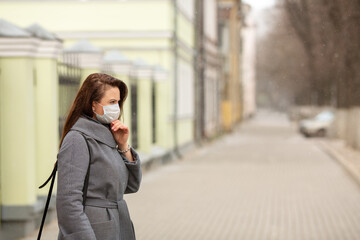 Obraz premium Woman wearing protective medical mask an empty European street, outdoors. Concept self-care - Image