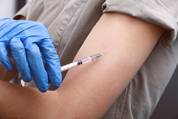 Female doctor or nurse giving shot or vaccine to a patient's shoulder. Vaccination and prevention against flu or virus pandemic.