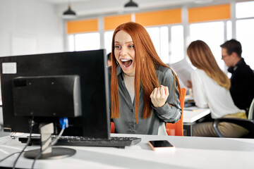 female office worker woman has wow reaction sitting at office desk and looking at computer screen, she is surprised excited receive good online results