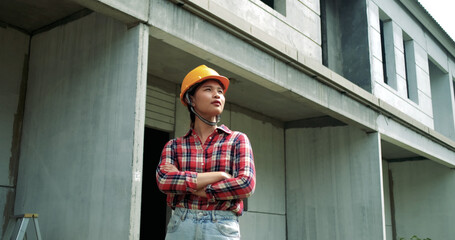 Portrait of young asian woman engineer safety equipment at construction site. Plan of construction site from ration with other worker and wearing safety equipment helmet and yellow glasses.