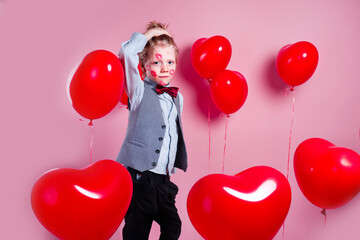 Valentines day. Funny little boy with red kisses on the skin in red balloons in the shape of a heart