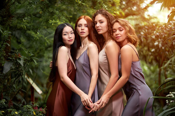 Obraz premium models around green fresh plants, slim slender female in rainforest. women posing at camera wearing silk elegant dress. people and nature