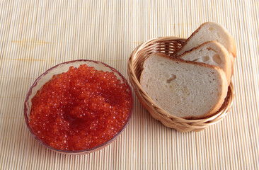 Red caviar lies on bread. Object on a wooden background