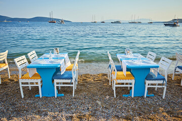 Fototapeta na wymiar Cute chairs and table on the beach at seaside restaurant in Bodrum
