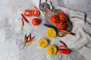 Italian food concept. Ingredients for cooking pasta. Dry pasta, cherry tomatoes, on grey background