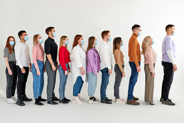 men and women wearing medical face mask, stand in a row, queue, isolated over white studio background. global society. disease epidemic, coronavirus infection concept