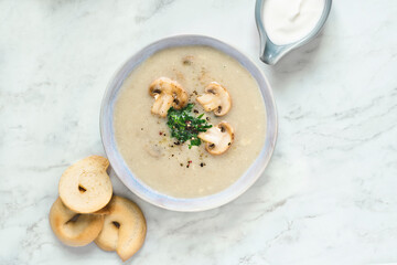 Creamy Champignon mushroom
 soup served with cream and croutons on a white marble background